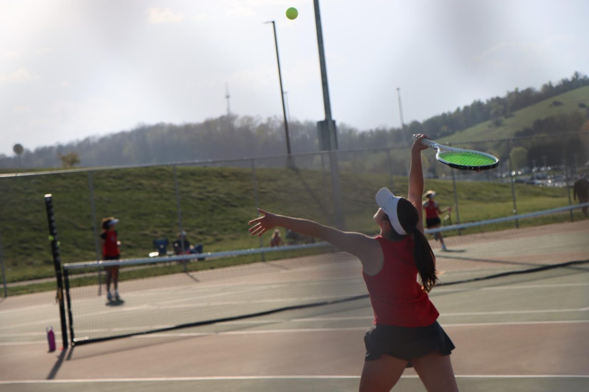Eleanor Troxell tosses the ball up and is about to serve to her opponent . 
