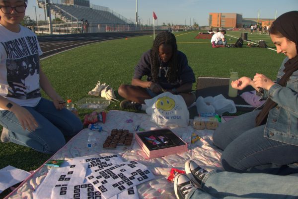 Senior Oreoluwa Akinyemi sits on a picnic rug to do henna and other activities for senior sunset. 